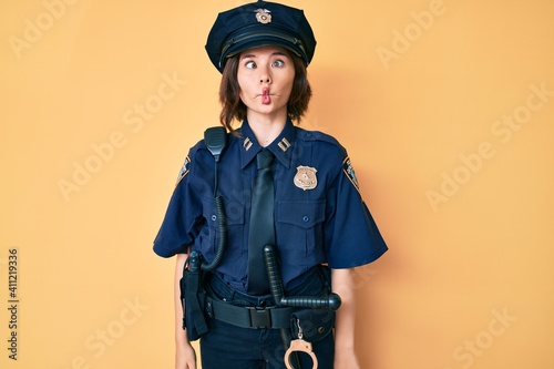 Fotografie, Obraz Young beautiful woman wearing police uniform making fish face with lips, crazy and comical gesture