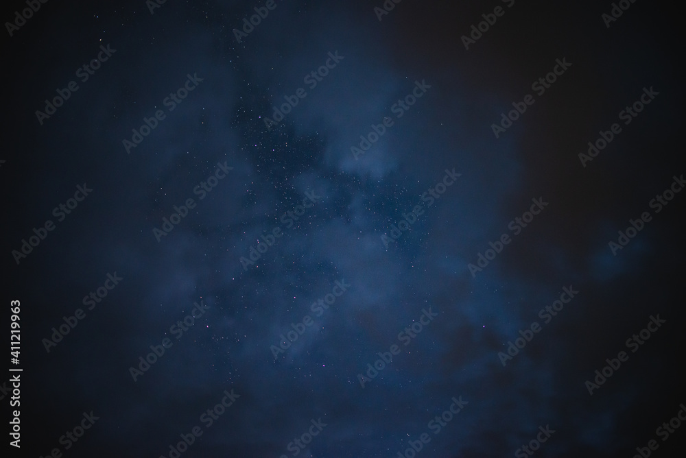 Stars in the night sky through the clouds on a summer night