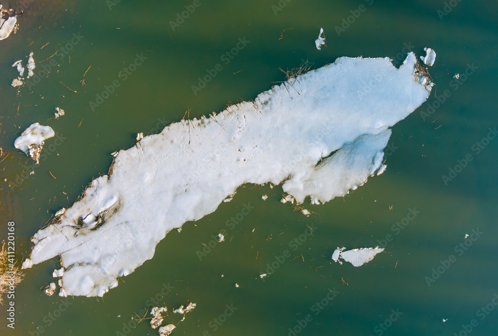Pieces of melting ice under the bright spring sun on the river bank