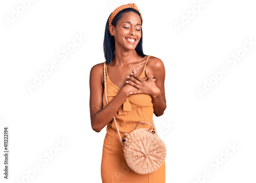 Young african american woman wearing summer outfit smiling with hands on chest with closed eyes and grateful gesture on face. health concept. photo