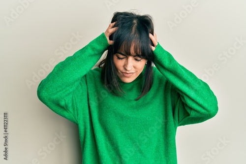 Young hispanic woman wearing casual winter sweater suffering from headache desperate and stressed because pain and migraine. hands on head. © Krakenimages.com