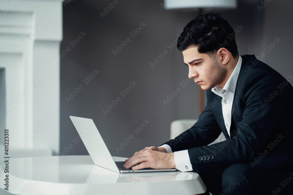 prints the text message to the partner. a professional manager works on a laptop computer. A man is sitting in a chair in a modern office. an administrator in a finance company. prints the text message to the partner. a professional manager works on a laptop computer. A man is sitting in a chair in a modern office. an administrator in a finance company.
