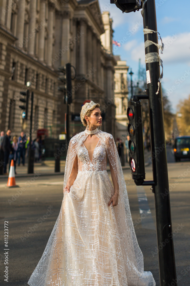 Obraz premium bride in ivory wedding dress stands by traffic lights, background buildings, street