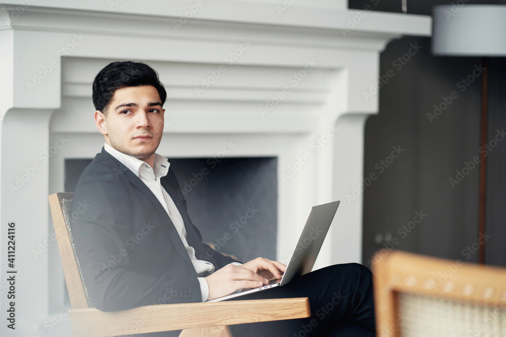 a trader works on a laptop, buys shares of companies. A man of Italian appearance is sitting in a chair in a modern office. the chief administrator of the company's finances a trader works on a laptop, buys shares of companies. A man of Italian appearance is sitting in a chair in a modern office. the chief administrator of the company's finances