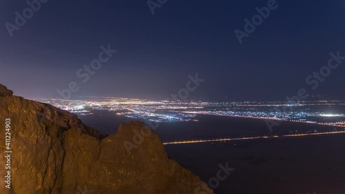 Day to night transition timelapse with rocks and road traffic on Jebel Hafeet. Mountain located primarily in the environs of Al Ain and offers an impressive view over the city. Aerial view from top photo