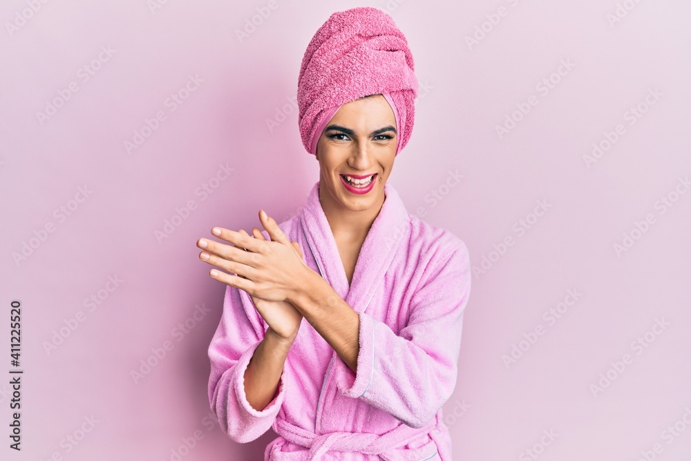 Young man wearing woman make up wearing shower towel on head and bathrobe clapping and applauding happy and joyful, smiling proud hands together Young man wearing woman make up wearing shower towel on head and bathrobe clapping and applauding happy and joyful, smiling proud hands together