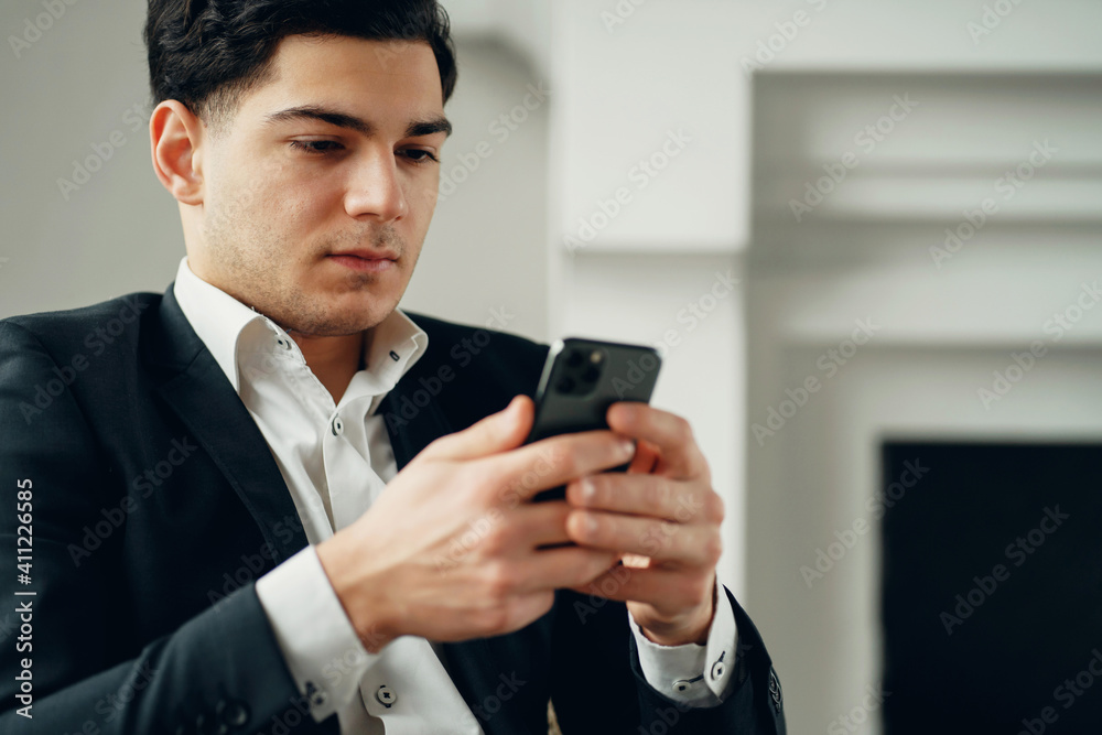 chat in a social network chat with friends and partners. The manager is a man in a business suit sitting in a modern office. prints a text message in the phone. a convenient application. chat in a social network chat with friends and partners. The manager is a man in a business suit sitting in a modern office. prints a text message in the phone. a convenient application.