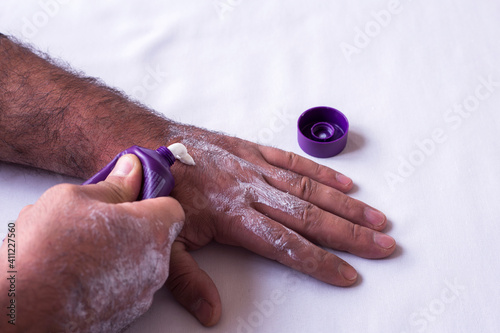 Young man hands using moisturizing white cream © Vahagn