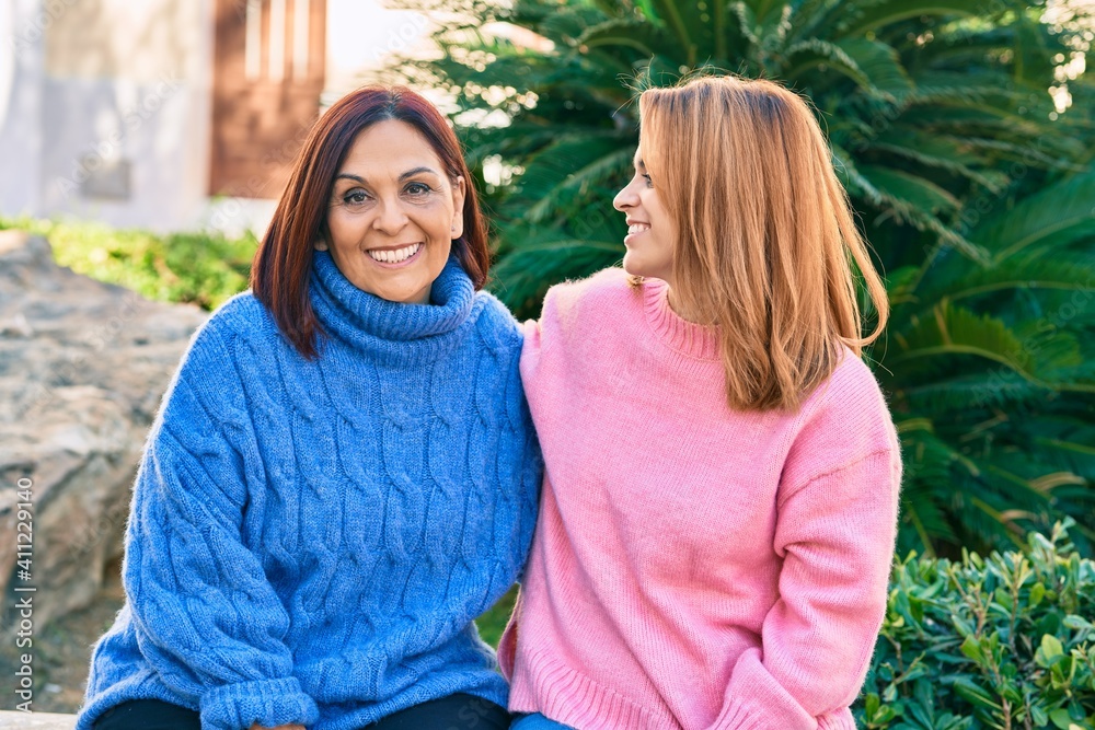 Fototapeta premium Hispanic mother and daughter smiling happy and hugging at the park.