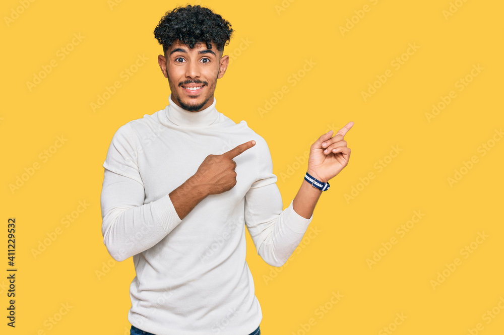 Young arab man wearing casual winter sweater smiling and looking at the camera pointing with two hands and fingers to the side. Young arab man wearing casual winter sweater smiling and looking at the camera pointing with two hands and fingers to the side.