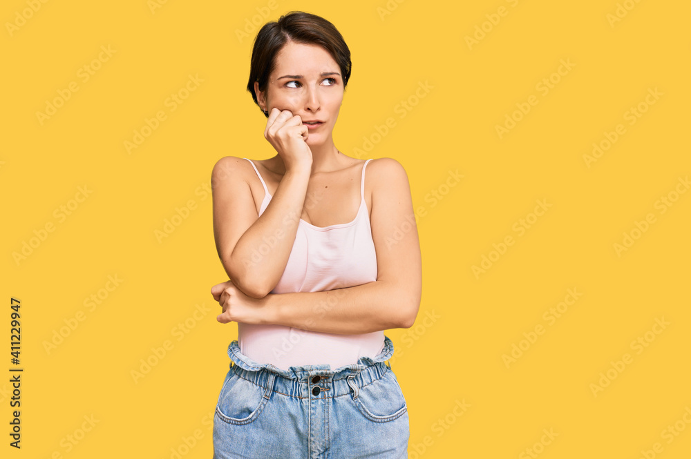 Young brunette woman with short hair wearing casual summer clothes looking stressed and nervous with hands on mouth biting nails. anxiety problem. Young brunette woman with short hair wearing casual summer clothes looking stressed and nervous with hands on mouth biting nails. anxiety problem.