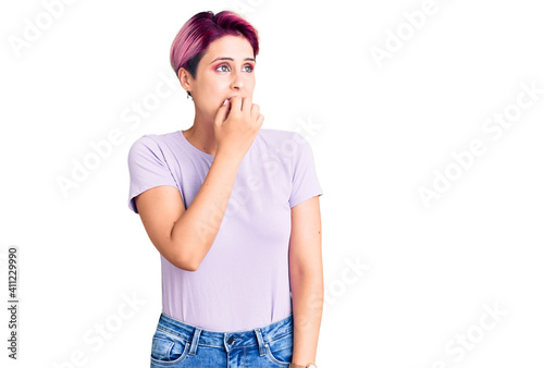 Young beautiful woman with pink hair wearing casual clothes looking stressed and nervous with hands on mouth biting nails. anxiety problem.