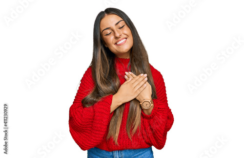 Beautiful hispanic woman wearing casual clothes smiling with hands on chest with closed eyes and grateful gesture on face. health concept.