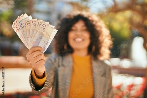 Young hispanic businesswoman smiling happy holding swedish krone banknotes at the city. photo