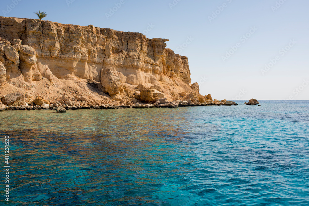 beautiful seascape with clear turquoise and blue water and bright yellow rocks off the coast of Sharm El Sheikh in egypt
