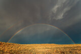 Landscape with a colorful rainbow in stormy sky, Kalahari desert, South Africa.