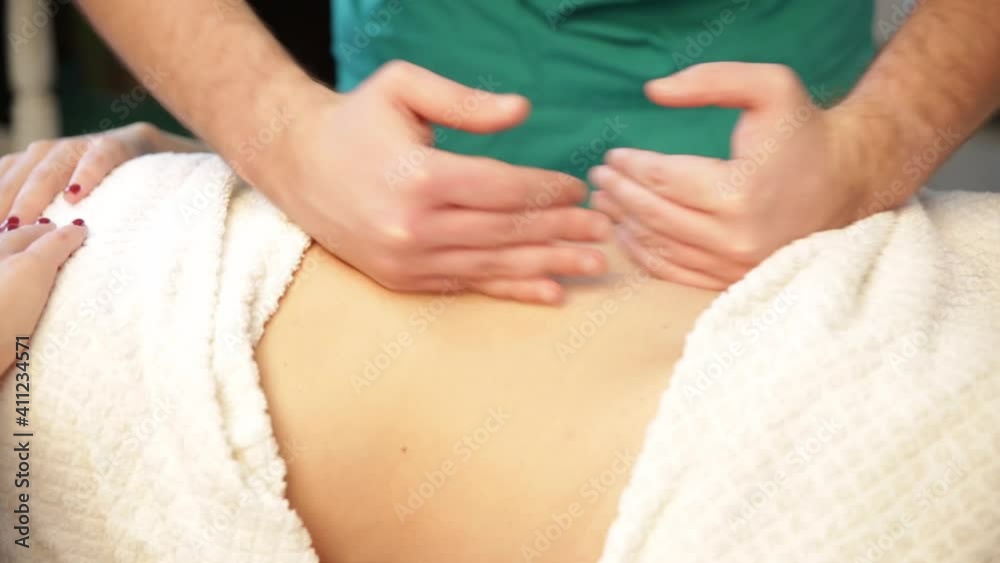 Hands of a masseur man doing a massage of the abdomen