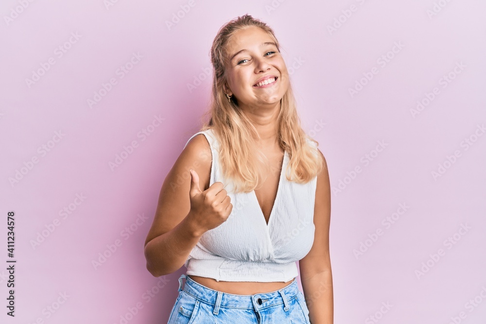 Young blonde girl wearing casual clothes doing happy thumbs up gesture with hand. approving expression looking at the camera showing success. Young blonde girl wearing casual clothes doing happy thumbs up gesture with hand. approving expression looking at the camera showing success.