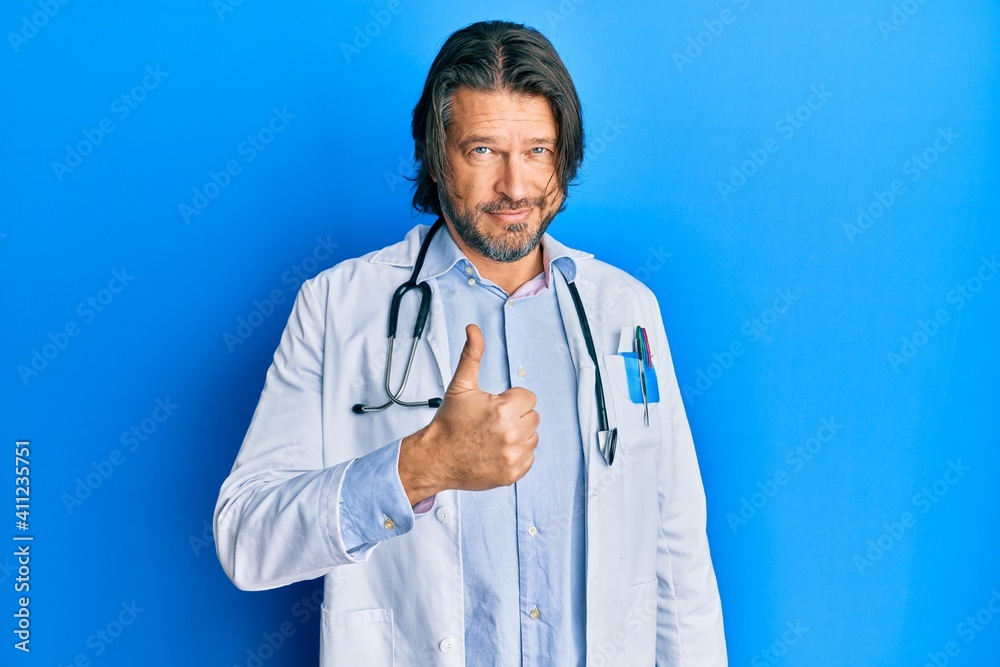 Middle age handsome man wearing doctor uniform and stethoscope doing happy thumbs up gesture with hand. approving expression looking at the camera showing success. Middle age handsome man wearing doctor uniform and stethoscope doing happy thumbs up gesture with hand. approving expression looking at the camera showing success.