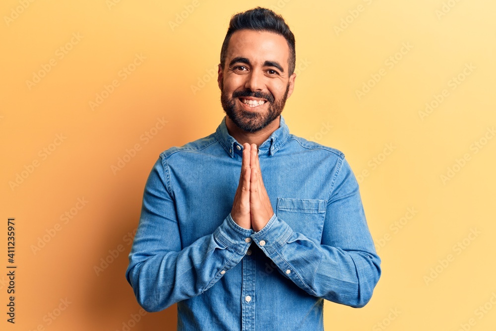 Young hispanic man wearing casual clothes praying with hands together asking for forgiveness smiling confident. Young hispanic man wearing casual clothes praying with hands together asking for forgiveness smiling confident.