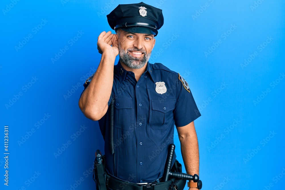 Middle age handsome man wearing police uniform smiling with hand over ear listening an hearing to rumor or gossip. deafness concept.