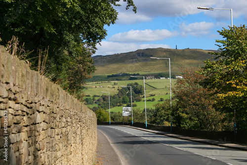 Mossley, England - A view of the rolling hills beside streetlights and an ancient wall on the outskirts of Mossley, under an idyllic blue sky.  Image has copy space.