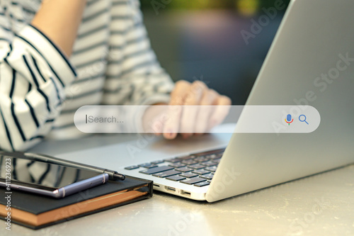 Search Engine Optimization - SEO concept. Closeup of a female hands using laptop computer with a smartphone on the table. Machine learning, AI Artificial intelligence, Smart search, Keyword research. photo