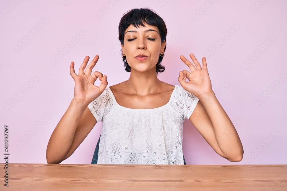 Beautiful brunettte woman wearing casual clothes over pink background relax and smiling with eyes closed doing meditation gesture with fingers. yoga concept. Beautiful brunettte woman wearing casual clothes over pink background relax and smiling with eyes closed doing meditation gesture with fingers. yoga concept.