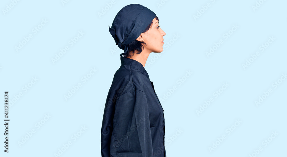 Young brunette woman with short hair wearing professional cook uniform looking to side, relax profile pose with natural face with confident smile. Young brunette woman with short hair wearing professional cook uniform looking to side, relax profile pose with natural face with confident smile.
