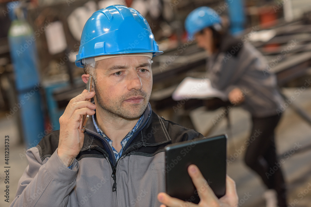 Worker announces at phone a worried new that he is reading on on his tablet Worker announces at phone a worried new that he is reading on on his tablet