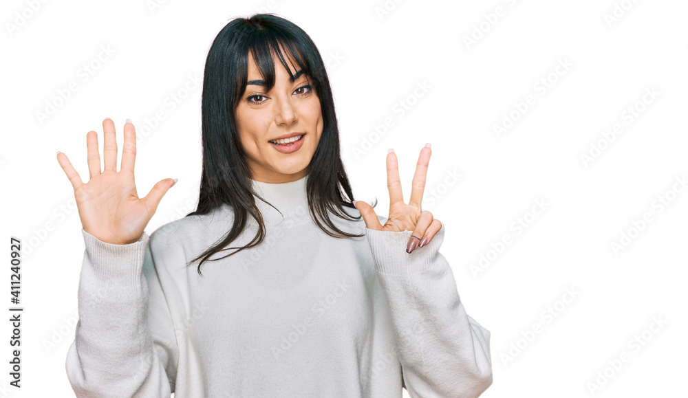 Young brunette woman with bangs wearing casual turtleneck sweater showing and pointing up with fingers number eight while smiling confident and happy. Young brunette woman with bangs wearing casual turtleneck sweater showing and pointing up with fingers number eight while smiling confident and happy.