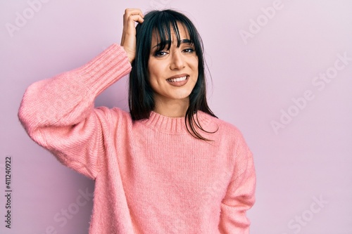 Young brunette woman with bangs wearing casual winter sweater confuse and wonder about question. uncertain with doubt, thinking with hand on head. pensive concept. © Krakenimages.com