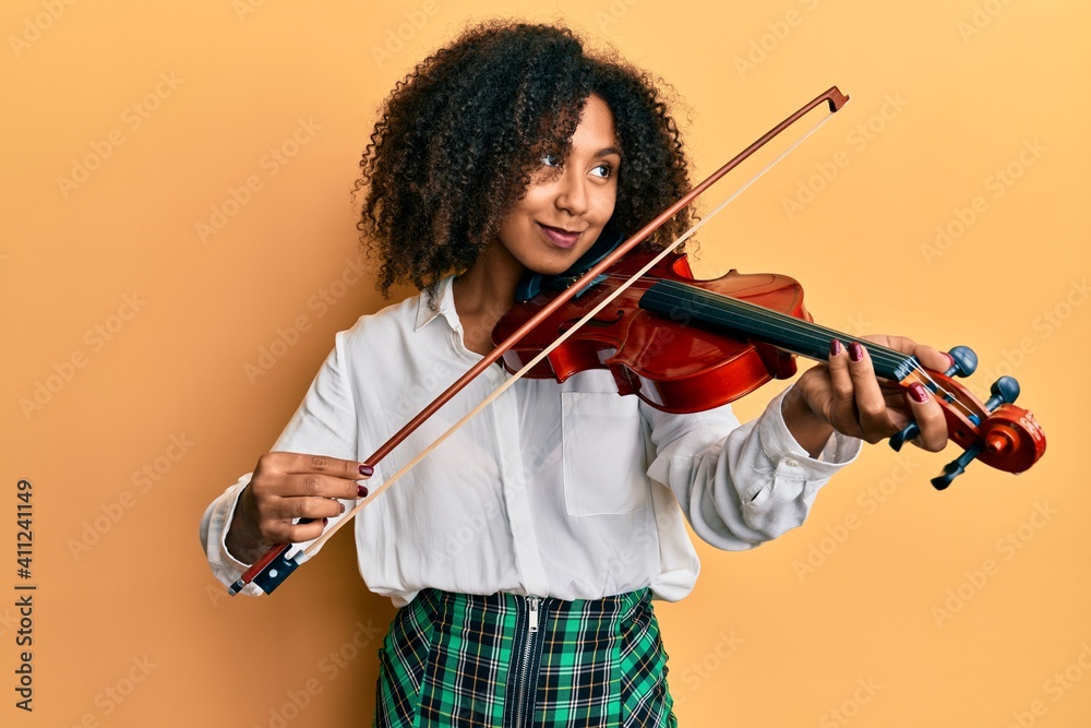 Φωτογραφία Beautiful african american woman with afro hair playing classical violin smiling looking to the side and staring away thinking