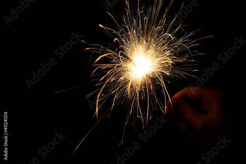 New year sparkler in hands on black background