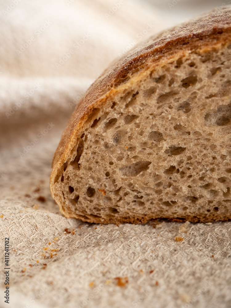 Homemade fresh wheat-rye bread on sourdough on a natural color linen napkin on a white background in the morning light
