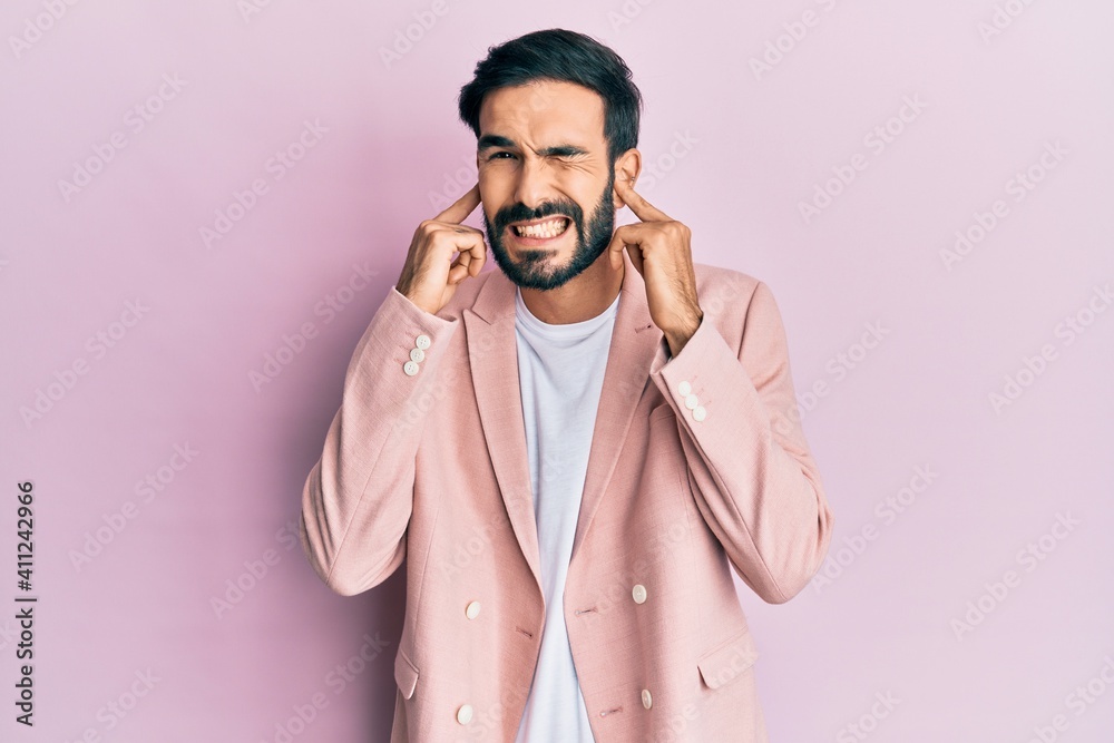 Young hispanic man wearing business jacket covering ears with fingers with annoyed expression for the noise of loud music. deaf concept. Young hispanic man wearing business jacket covering ears with fingers with annoyed expression for the noise of loud music. deaf concept.