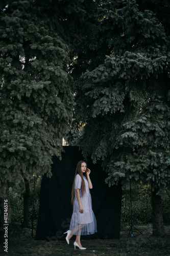 Girl in a dress in nature on a black background attached to the racks