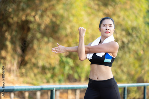 young fitness woman exercising and stretching arms, workout in the park