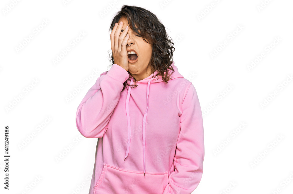 Young hispanic woman wearing casual sweatshirt yawning tired covering half face, eye and mouth with hand. face hurts in pain. Young hispanic woman wearing casual sweatshirt yawning tired covering half face, eye and mouth with hand. face hurts in pain.