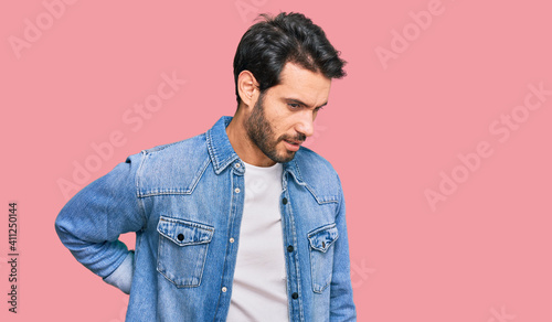 Young hispanic man wearing casual clothes suffering of backache, touching back with hand, muscular pain