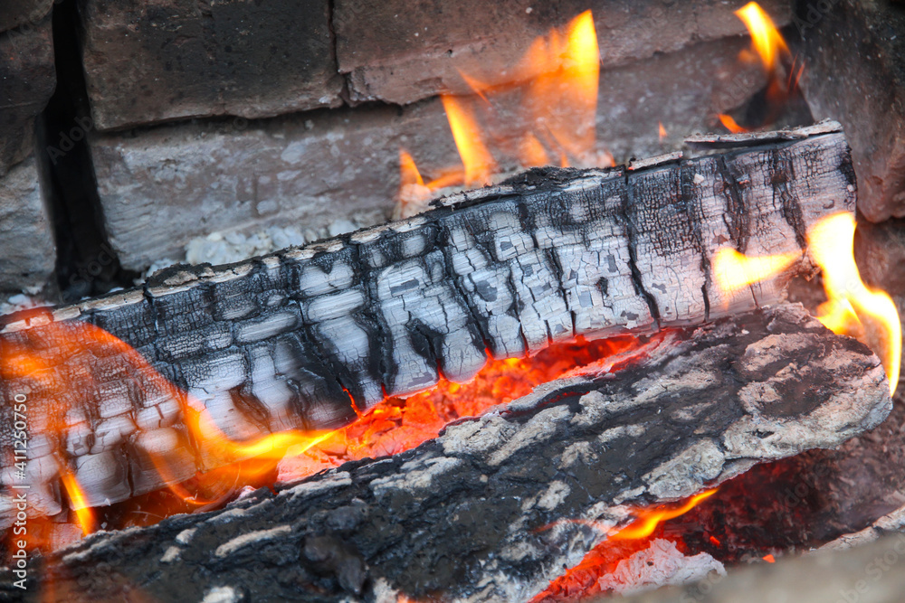 Fototapeta premium Glowing embers in hot red color, abstract background. The hot embers of burning wood log fire. Firewood burning on grill. Texture fire bonfire embers.