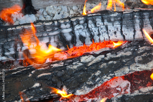 Glowing embers in hot red color, abstract background. The hot embers of burning wood log fire. Firewood burning on grill. Texture fire bonfire embers.