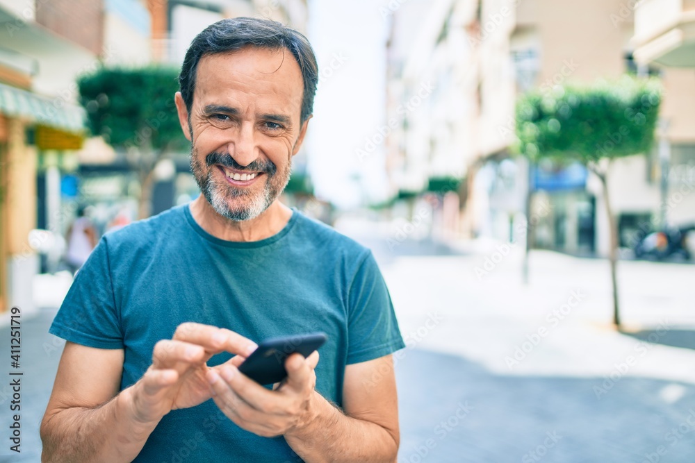 Middle age man with beard smiling happy outdoors using smartphone - obrazy, fototapety, plakaty 