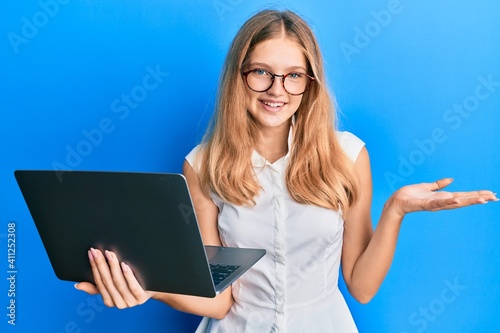 Beautiful young caucasian girl working using computer laptop celebrating achievement with happy smile and winner expression with raised hand