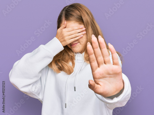 Beautiful young caucasian girl wearing casual sweatshirt covering eyes with hands and doing stop gesture with sad and fear expression. embarrassed and negative concept.