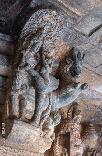 Badami, Karnataka, India - November 7, 2013: Cave temples above Agasthya Lake. Gray stone statue as crown on pillar of couple in erotic position, with wild horse on the side in cave 3.