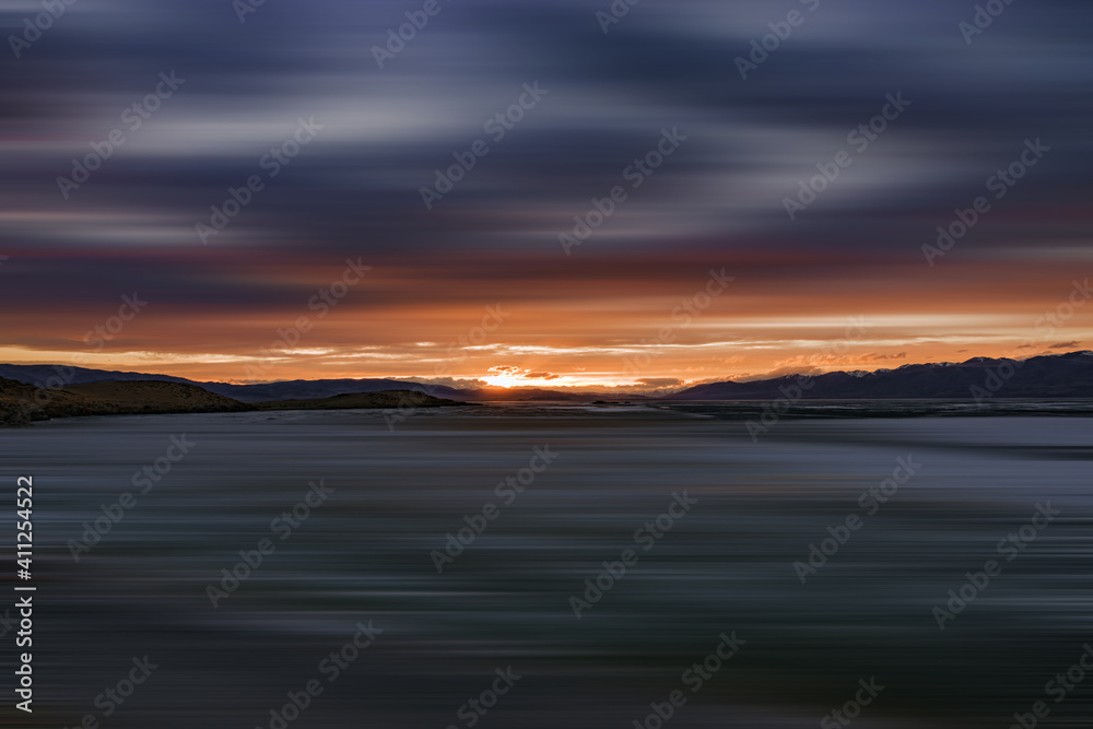 blurred view of plain at root of snow-covered mountains at sunset 