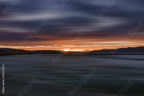 blurred view of plain at root of snow-covered mountains at sunset 