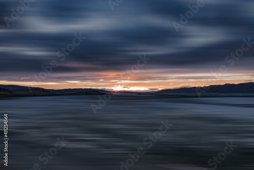 blurred view of sea surrounded by rocky coast with snow-covered summits