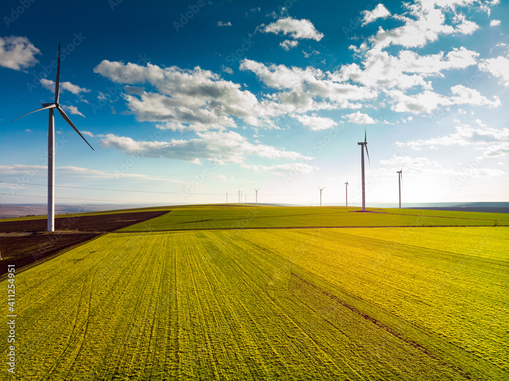 Obraz premium Beautiful bright Landscape with a Windfarm on a sunny day with a sky full of clouds and colorful foreground with green-yellowish grass